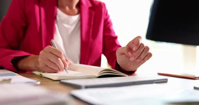 Woman writes with pen in diary on computer keyboard. Business and educational concept