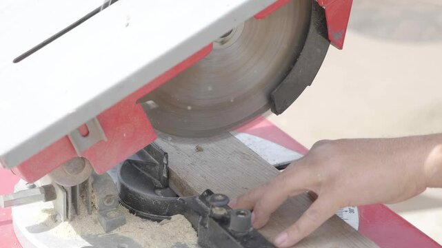 A middle-aged man using a table saw to precisely cut wood for a playground he is building in the garden. The scene emphasizes his meticulous craftsmanship.
