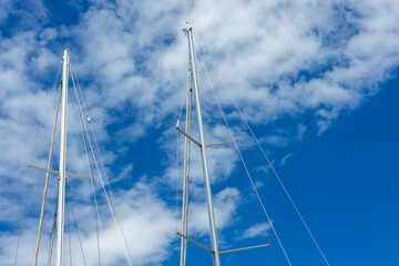 Obraz premium The tops of the yacht's masts against the bright sky.