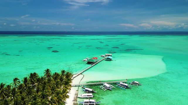 Onok Island in Balabac shows a white sandbar pier outrigger boats palm trees and turquoise shallow water under a clear tropical sky