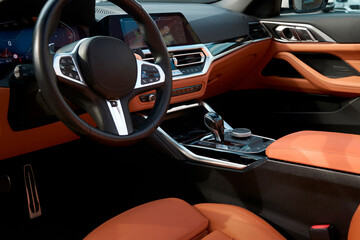 A view of the dark dashboard from the driver's seat, with a close-up of the steering wheel in the foreground. The interior is brown with black accents