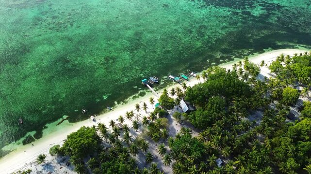 High aerial of Candaraman Island in Balabac Palawan Philippines with palm shoreline white sand beach piers and shallow reef