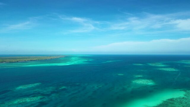 Wide aerial seascape off Bugsuk Island in Balabac Palawan Philippines with reef patches turquoise shoals and blue horizon