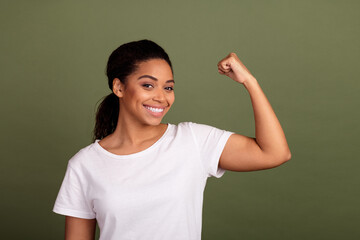 Portrait photo of young attractive woman with ponytail brunette hair showing muscle raised fist up...