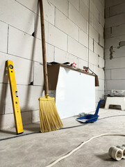A level, a broom, a dustpan, and an extension cord were on the construction site for a house made from aerated concrete