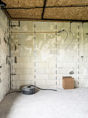 A roll of cable and a box against the backdrop of an aerated concrete wall at a house under construction