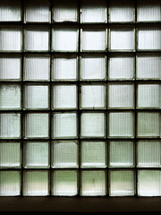 A window made of green glass blocks in a dark room