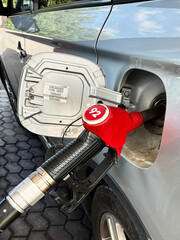 Refueling a silver car with a red gasoline pump with 92 octane at a gas station