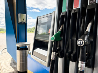 Refueling pumps in red, green, and black at the gas station, with gasoline. The black pump has the letter "DT" on it