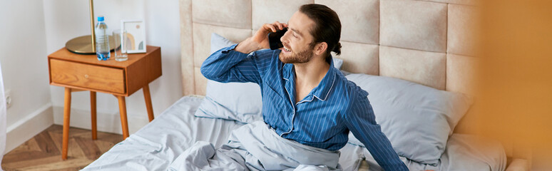 A man sitting on a bed, chatting on a cell phone.