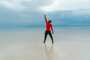 athlete raising his arms in the air on the beach