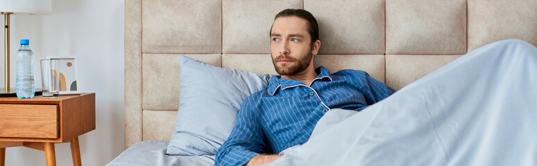 A man lays in bed, draped in a sheet, relaxing and rejuvenating.