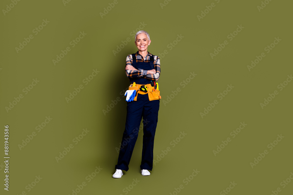 Sticker Full size photo of senior female professional expert handyman folded hands wear blue workwear overall isolated on khaki color background