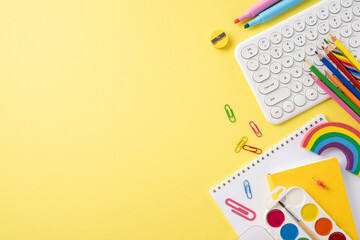 Top view of various school stationery items on a bright yellow background symbolizing back to school preparations