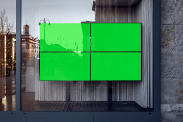 Obraz premium Four Widescreen TVs With Green Screen Mockups For Banners And Branding. Empty Store Showcase With Blank Advertising Billboards