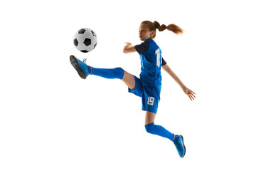 Concentrated teen girl, soccer player in blue uniform kicking ball in motion in jump isolated on...