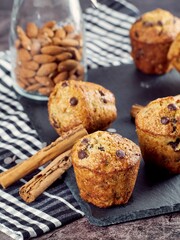 Close-up of a freshly banana vegan chocolate chip cupcake on a slate board with cinnamon sticks