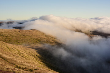 Top view from Pen y Fan, a highest point in Brecon Beacons, or Bannau Brycheiniog, the National Park in Wales. Mountains covered in clouds. Landscape photograph. 