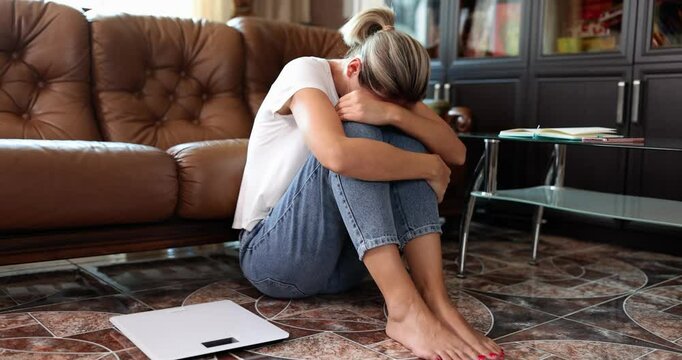 Woman suffering from depression and neurosis sits on floor and cries. Overweight stress and hormonal failure