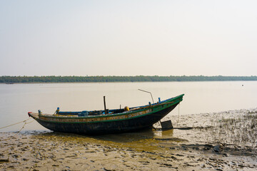 Fototapeta premium A traditional fishing boat is seen on a water creek on the coast of the Sundarbans delta. Concept of fishing and environment in Indian Sundarbans region