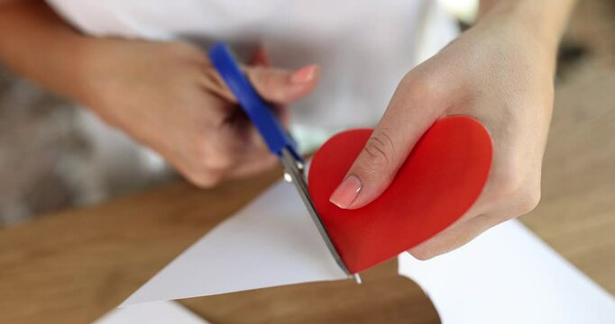 Woman hands cut out red heart from paper. Gift concept for Valentine Day and Mother Day