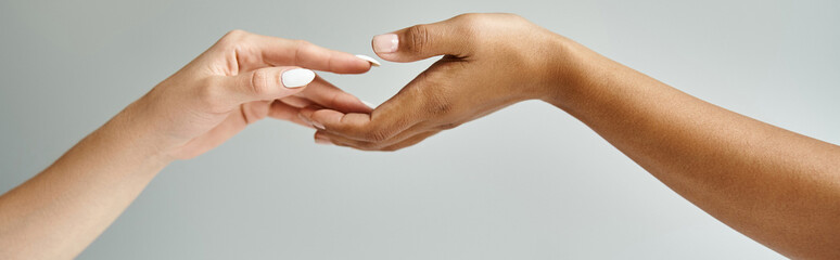 Two beautiful diverse women hold hands, fingers entwined in a gentle embrace.