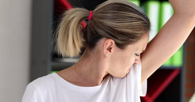 Portrait of woman sniffing her armpit and disgusted by smell of sweat. Hygiene and health care