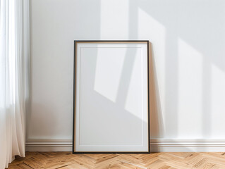 Black blank frame A4 format standing on the floor near the white wall. Trendy minimalist frame mockup for posters, prints. 