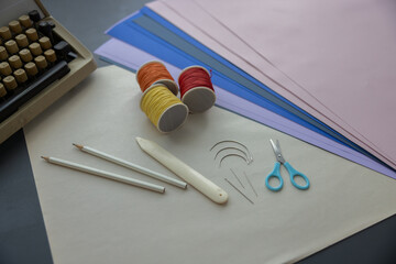 High-quality image of a person binding a book using traditional coptic stitch technique. DIY bookbinding, handcrafting, artisan book, handmade, coptic stitch, binding tools, creative, detailed process