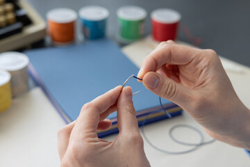 High-quality image of a person binding a book using traditional coptic stitch technique. DIY bookbinding, handcrafting, artisan book, handmade, coptic stitch, binding tools, creative, detailed process