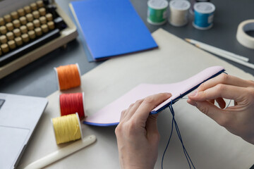 High-quality image of a person binding a book using traditional coptic stitch technique. DIY...