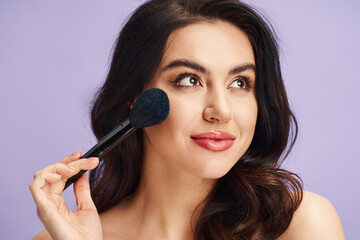 A woman with natural beauty delicately holds a brush to her face.