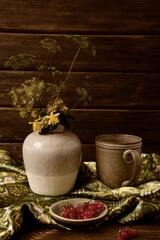Still life of ceramic dishes, branches and red currants on a green background.