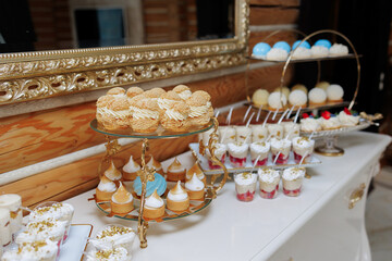 A table with a variety of desserts, including cupcakes, cakes, and pastries. The desserts are arranged on a white table and are displayed in a way that makes them look appealing and inviting