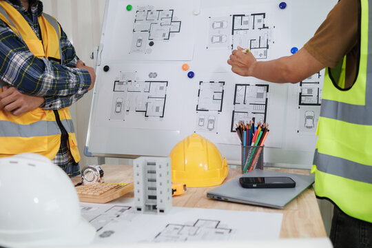 A team of engineers and architects discuss house plan design and estimate construction prices to suit the construction budget. Checking blueprints and documents with a team of engineers and architects
