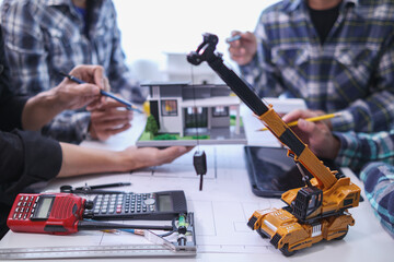 team of engineers and architects discuss house plan design and estimate construction prices to suit the construction budget. Checking blueprints and documents with a team of engineers and architects