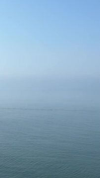 Calm blue sea and sky at early morning, vertical video.