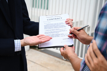 Sealing the Deal, A close-up of a new homeowner signing the contract, guided by the real estate...