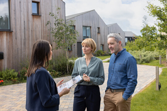 Real estate agent giving property details of an eco home to a mature couple