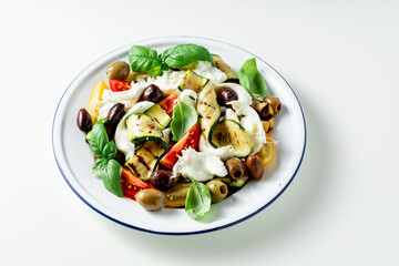 Mediterranean salad with mozzarella, olives, basil and grilled vegetables on white