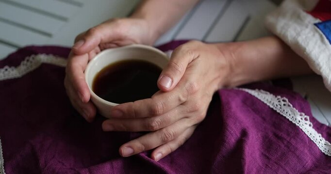 Female hand on the white table with ceramic cup of coffee. Rest relax concept. Vintage village mood. Close up. video footage 4k