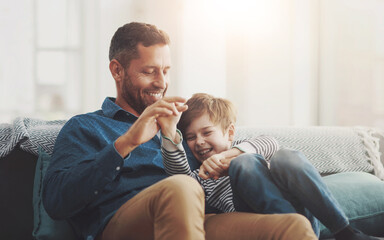 Father, boy and laughing on sofa together in home, bonding and hug for funny conversation. Daddy, son and happy family playing in living room for joke, talk and embrace for security in relationship