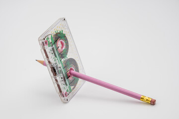 Old music magnetic cassette and wooden pencil on white background