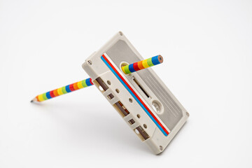 Old music magnetic cassette and wooden pencil on white background