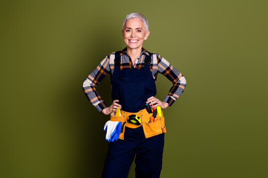 Photo portrait of pretty senior female professional expert handyman confident wear blue workwear overall isolated on khaki color background - Powered by Adobe