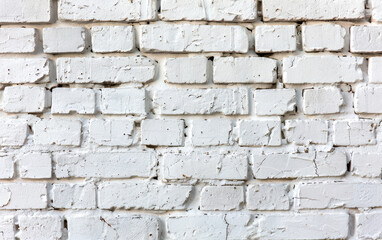 Fototapeta premium Close-up of a white painted brick wall texture with visible cracks and imperfections, perfect for backgrounds and design projects.