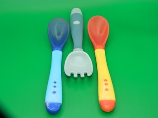 Macro photo of children's educational eating equipment on a green background.