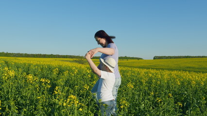 Fototapeta premium Farmer Family Scene Of Mom And Son Boy Inspect Rapeseed Crop. A Happy Family. Rapeseed Field. Harvest. Agricultural Business.
