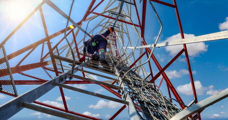Aerial view, technician climbing on a communication tower to repair an antenna