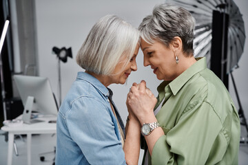 A mature lesbian couple shares a tender moment during a professional photo shoot.